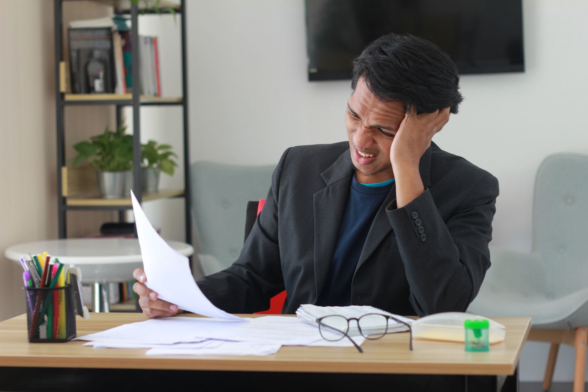 A business owner stressed by paperwork and manual admin tasks.